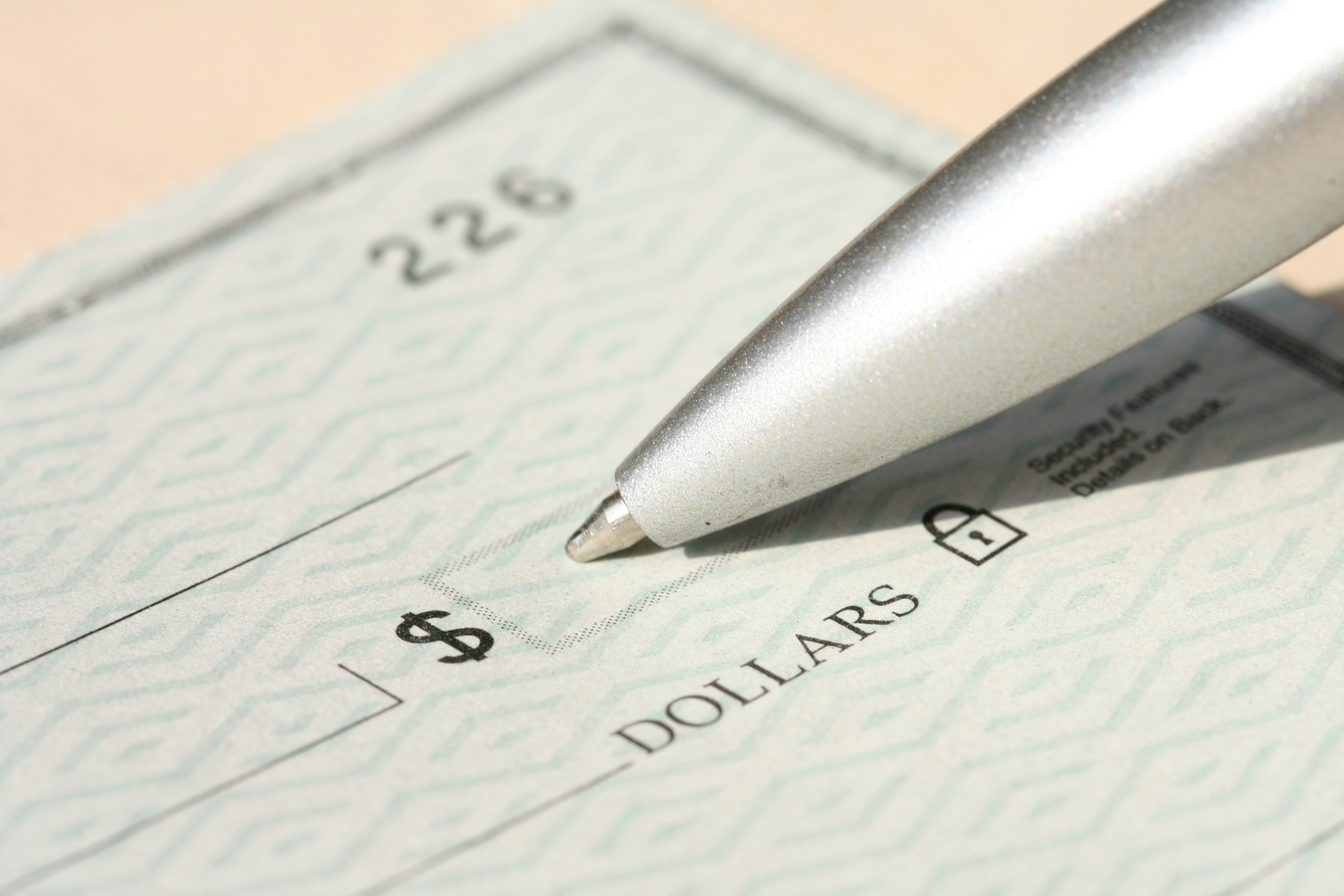 Pen filling out a blank check to represent federal grant reimbursement